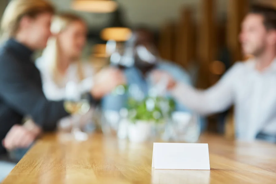 Gasten aan tafel in een restaurant, met een gereserveerd-kaartje op het hout